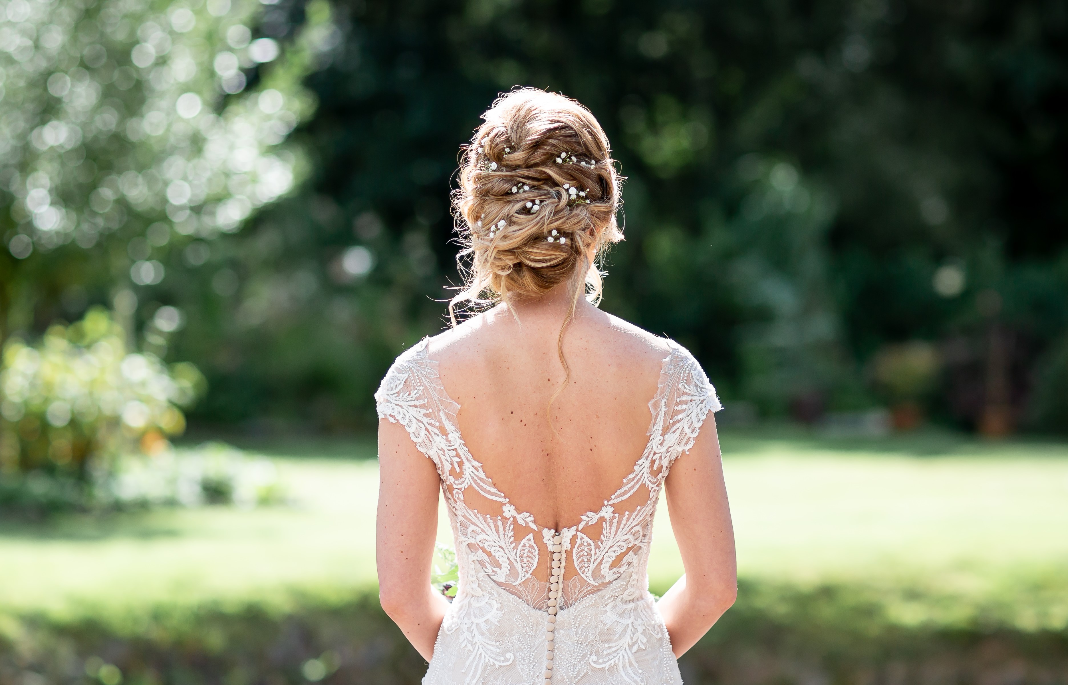 Bride seen from behind showing a soft low bridal updo and detailed dress back