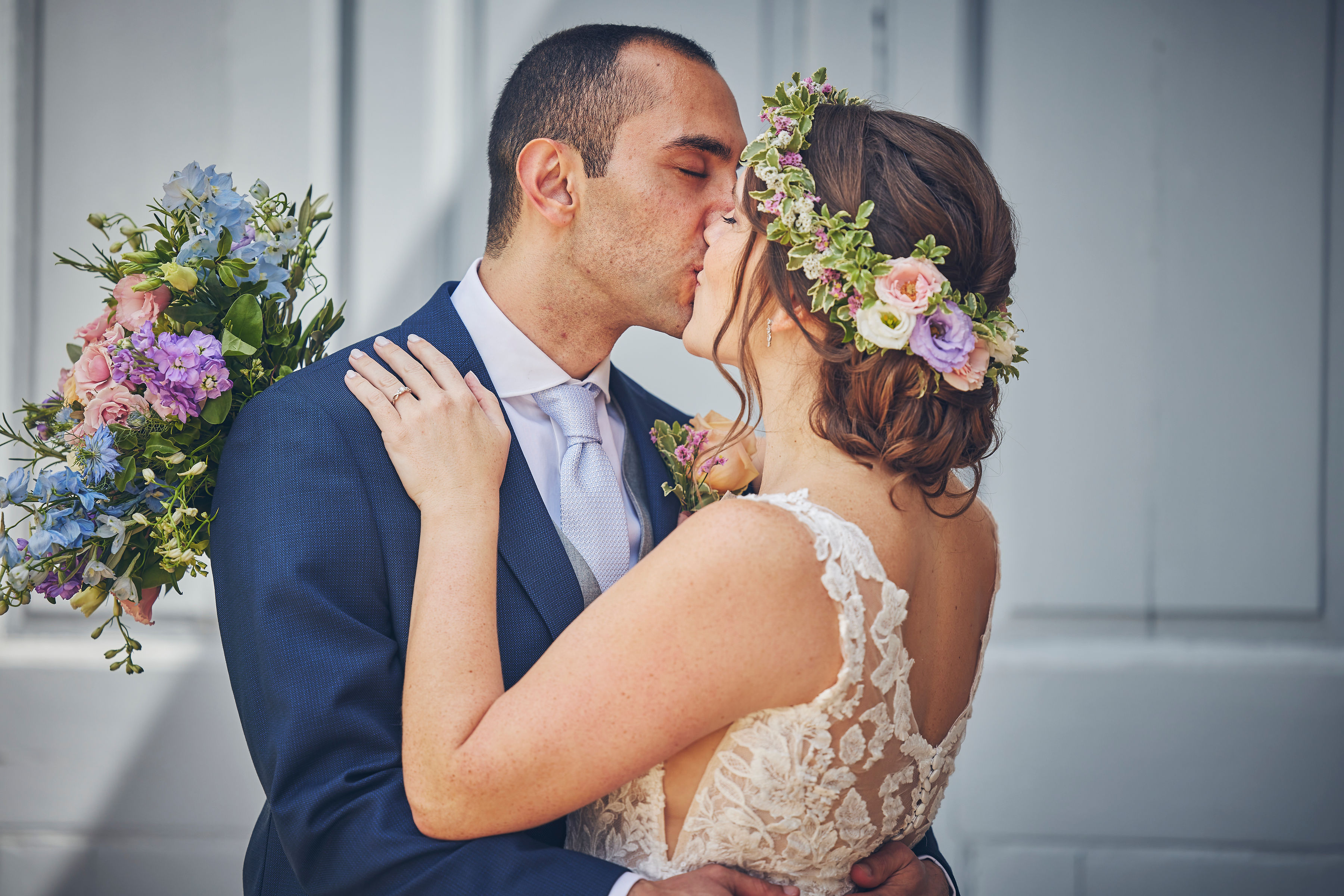 Couple kissing, the bride's floral hair detail visible from the back