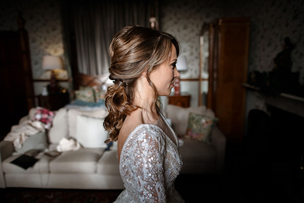 Side profile of a bride with a textured low updo and lace dress