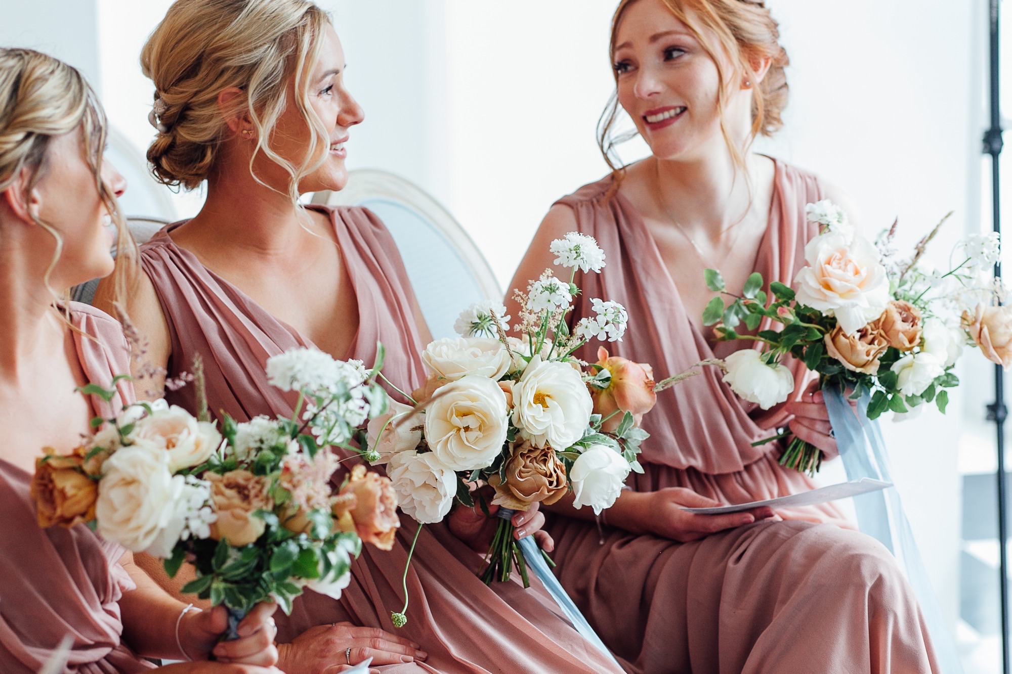 Bride with bridesmaids in pink robes holding bouquets